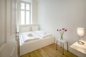 ein weißes Schlafzimmer mit einem Bett und einer Vase aus Blumen in der Unterkunft Newton-Appartement mit 3 Schlafzimmern in Berlin