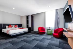a hotel room with a bed and two red chairs at SUPER OYO Capital O 472 Hotel Asyra in Makassar