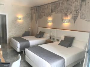 two beds in a hotel room with lights on the wall at Hotel Madeira Centro in Benidorm