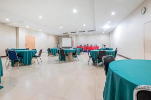 a conference room with green tables and chairs and a screen at SUPER OYO Capital O 472 Hotel Asyra in Makassar