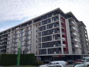 a large apartment building with cars parked in a parking lot at Apartament Rosso in Łódź