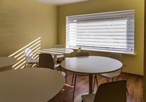 a classroom with tables and chairs and a window at Miego namai in Gargždai