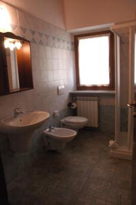 bagno con 2 lavandini, servizi igienici e finestra di Hotel Clari a Claviere