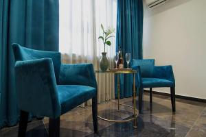 Zimmer mit blauen Stühlen, einem Tisch und einem Fenster in der Unterkunft Athens Imperial Suites - Luxury Living in Athen