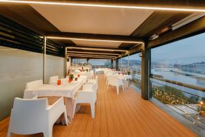 a restaurant with white tables and white chairs on a balcony at Abba Euskalduna Hotel in Bilbao