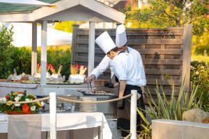 a couple of chefs preparing food on a grill at Relais Bellaria Hotel & Congressi in Bologna
