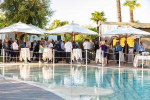 a group of people standing around a pool with umbrellas at Relais Bellaria Hotel & Congressi in Bologna