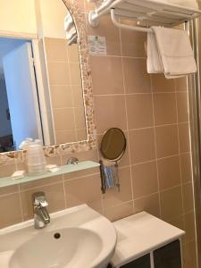 a bathroom with a sink and a mirror and a toilet at Hotel de la Plage Santa Vittoria in Algajola