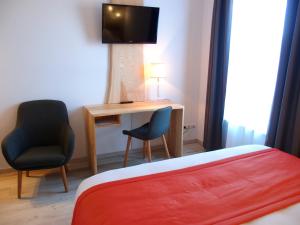 een slaapkamer met een bed, een bureau en een televisie bij Hostellerie de l'Étoile in Wasselonne