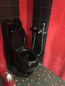 a black toilet in a bathroom with a red wall at Araksi HOSTING in Tallinn