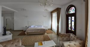 a bedroom with a bed and a couch and a window at Hotel Coquette in Măneciu
