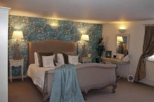 1 dormitorio con 1 cama con papel pintado de flores azul en The Queens Head en Belton