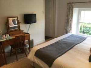 a bedroom with a bed and a desk and a television at Plume of Feathers in Blagdon