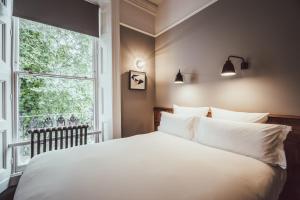 Un dormitorio con una gran cama blanca y una ventana en The Pilgrm en Londres