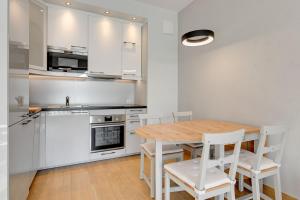 a kitchen with a wooden table and white chairs at Holiday Apartment near the Sea - free private parking in Gdańsk