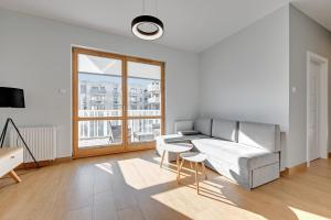 een witte kamer met een bed en een tafel en stoelen bij Holiday Apartment near the Sea - free private parking in Gdańsk