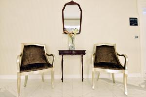 two chairs sitting next to a table with a mirror at Hotel Ziya in Podgorica