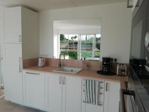 a kitchen with white cabinets and a sink and a window at Esprit Cottage "4 étoiles" sables d'Or les pins in Plurien