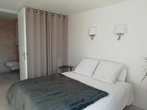 ein Schlafzimmer mit einem großen Bett mit weißen Wänden in der Unterkunft Esprit Cottage "4 étoiles" sables d'Or les pins in Plurien