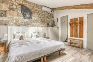 a bedroom with a large bed and a stone wall at Jolysable in Pons