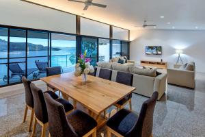 uma sala de estar com uma mesa de madeira e cadeiras em Waves 5 Luxury 3 Bedroom Breathtaking Ocean Views Central Location em Hamilton Island