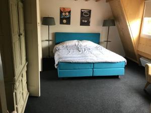 um quarto com uma cama azul e 2 candeeiros em Sonop em Oostkapelle