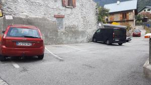 two cars parked in a parking lot next to a building at Gites de la combe in Bramans