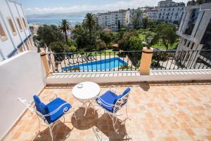 uma varanda com mesa e cadeiras e uma piscina em El Minzah Hotel em Tânger