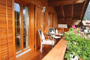 een houten veranda met een tafel en stoelen op een balkon bij Haus Ender in Sankt Gallenkirch