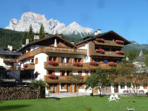 un edificio con balcones en él con montañas en el fondo en Appartamenti da Nica e Diego en Borca di Cadore
