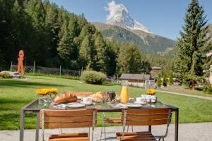a table with chairs and a mountain in the background at Chalet Altesse - Premium Apartments in Zermatt