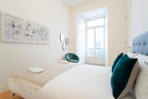 een witte slaapkamer met een groot bed en een raam bij FLH Chiado Modern Apartment in Lissabon