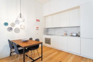 een keuken met witte kasten en een houten tafel bij FLH Chiado Modern Apartment in Lissabon