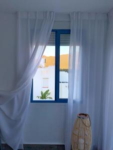 a window with white curtains and a vase in a room at Alojamientos 4nudos in San José