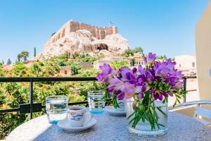 stół z wazonem z fioletowych kwiatów i okularów w obiekcie Phaedra Hotel w Atenach