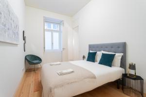 a white bedroom with a large bed with blue pillows at FLH Chiado Trendy Apartment in Lisbon