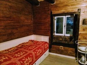 サン・ペードロ・ド・スーにあるRefúgio do Fujacoの木製の壁のベッドルーム1室、窓付きのベッド1台が備わります。