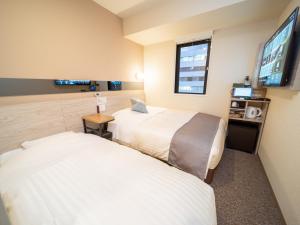 a hotel room with two beds and a flat screen tv at Super Hotel Premier Akihabara in Tokyo