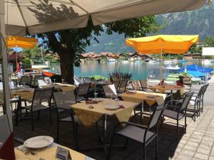 un groupe de tables avec chaises et parasols à côté d'un lac dans l'établissement Family-Apartment Du Lac, à Iseltwald