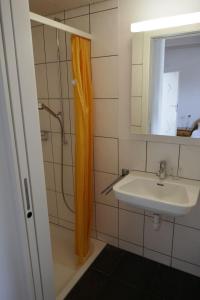 baño con cortina de ducha naranja y lavamanos en Zwinglis Ferienwohnung, en Nesslau