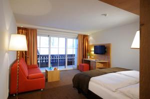 a hotel room with a bed and a chair and a window at Hotel Saalbacher Hof in Saalbach-Hinterglemm