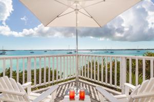 Un balcón con sillas, una sombrilla y el océano. en Peace and Plenty Resort, en Georgetown