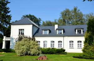 a white house with a black roof at Dwór w Zabużu in Zabuże