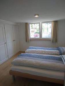 dwa łóżka w sypialni z dwoma oknami w obiekcie Zwinglis Ferienwohnung Klärli w mieście Nesslau
