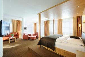 a bedroom with a bed and a living room at Hotel Saalbacher Hof in Saalbach-Hinterglemm