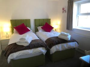 a bedroom with two twin beds with red pillows at Fabulous One Bedroom Apartment in Ripon City Centre in Ripon