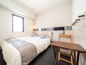 a bedroom with two beds and a table at Super Hotel Premier Akihabara in Tokyo