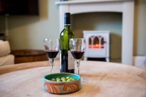 a bottle of wine and two wine glasses on a table at Gwalia House- Stunning Central Townhouse with 3 ensuite bedrooms in Laugharne