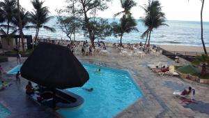 um grupo de pessoas sentadas em torno de uma piscina ao lado da praia em flat apt mobiliado beira mar no Recife