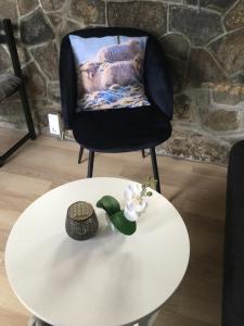 ein Stuhl und ein weißer Tisch mit einer Blume darauf in der Unterkunft Gróthusið in Sørvágur